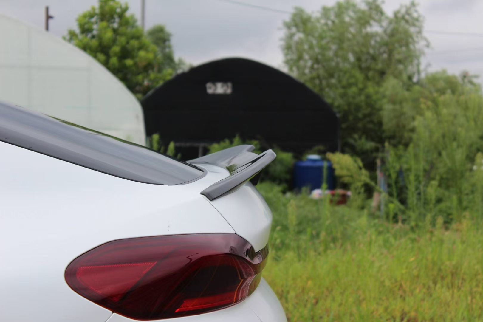 Front view of a white BMW X6M featuring an aggressive REVOZPORT front bumper and carbon fiber aero styling parked on a quiet urban street.