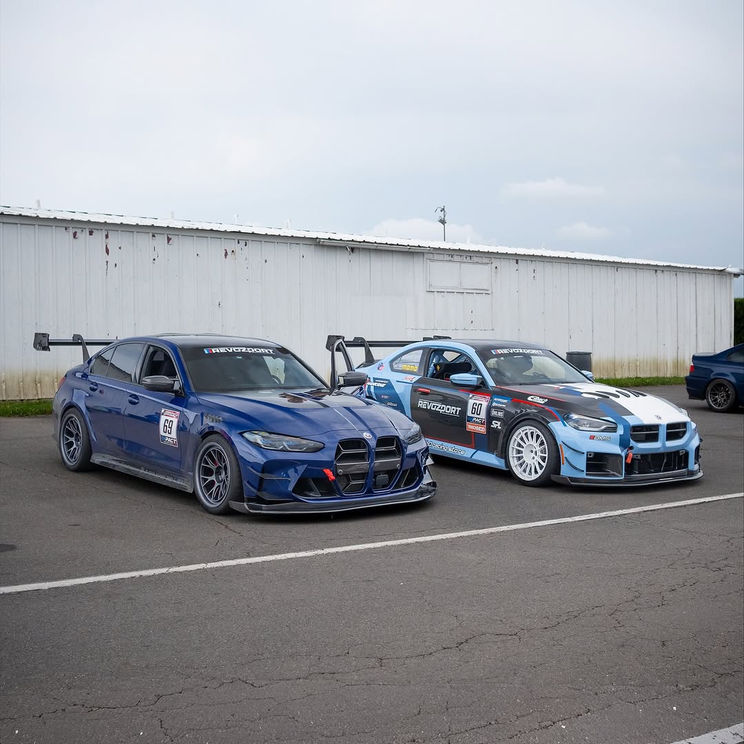 Close-up of a blue wide-body performance car featuring aggressive aerodynamic fender vents, extended side skirts, and lightweight multi-spoke wheels. The image highlights the custom bodywork, low-profile performance tire, and carbon fiber aero details in an outdoor automotive setting.