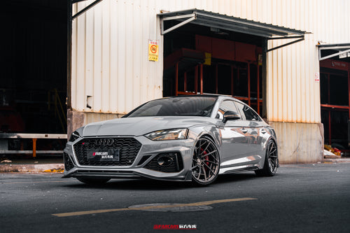 Gray Audi RS5 Sportback fitted with REVOZPORT forged multi-spoke wheels, parked outside an industrial garage.