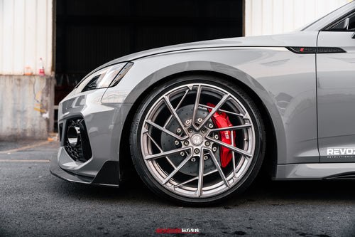 Gray Audi RS5 Sportback fitted with REVOZPORT forged multi-spoke wheels, parked outside an industrial garage.