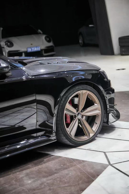 Black Audi RS4 Avant featuring a REVOZPORT carbon fiber body kit with front lip, side skirts, and aggressive aero styling displayed inside a luxury showroom.