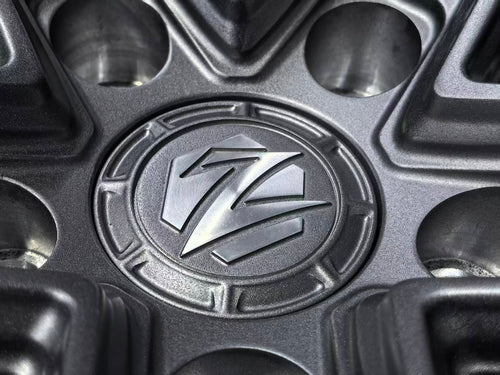 Matte gray REVOZPORT forged alloy wheel with an intricate split multi-spoke design displayed on a black textured workshop floor.