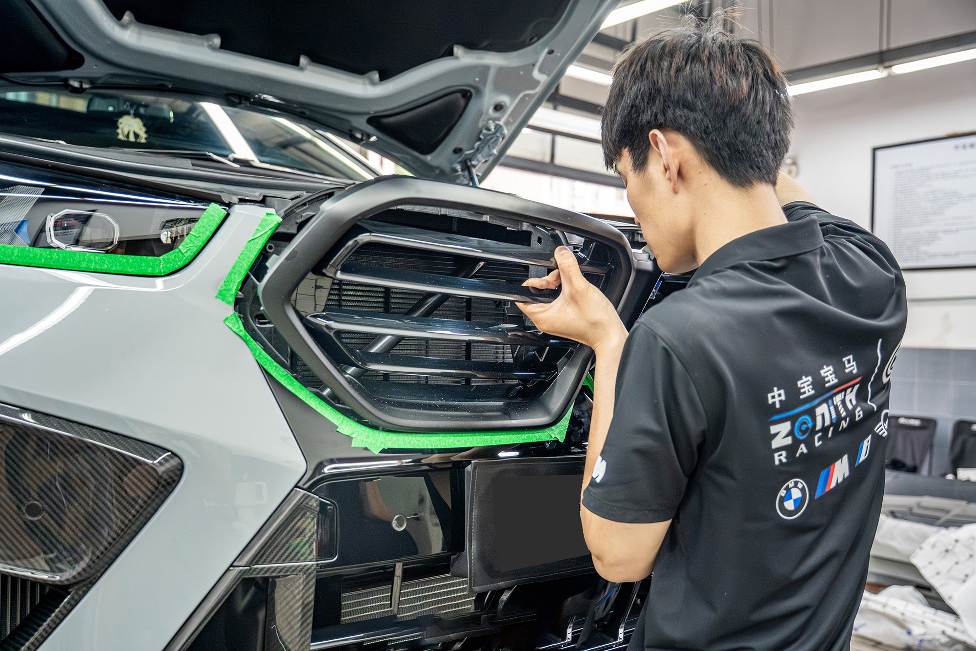 Professional installation process showcasing precise grille alignment, carbon fiber aero integration, and meticulous workshop craftsmanship on a high-performance BMW build.