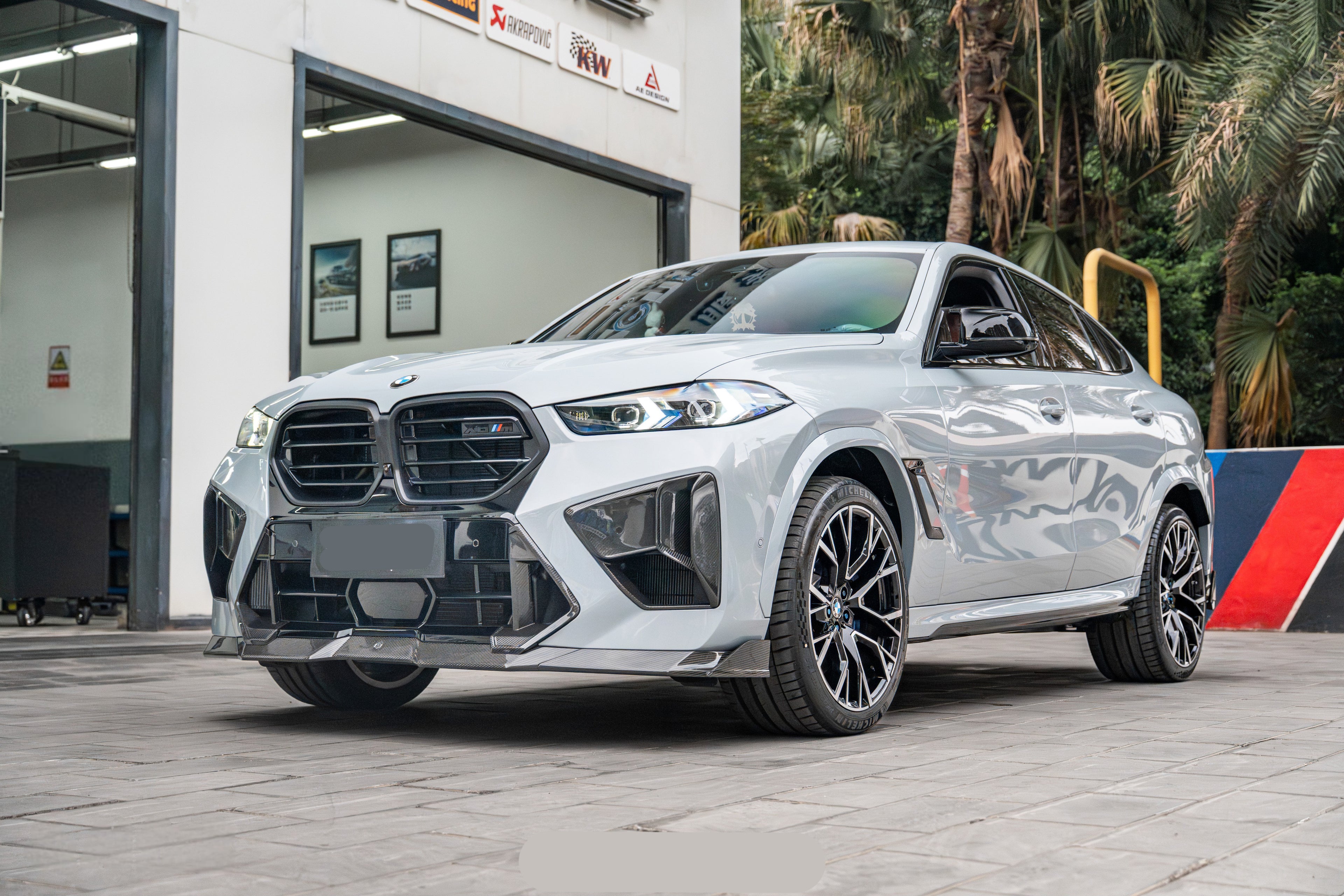 Aggressive carbon fiber aero styling paired with sharp body lines and premium wheel fitment, captured outside a professional performance workshop setting.
