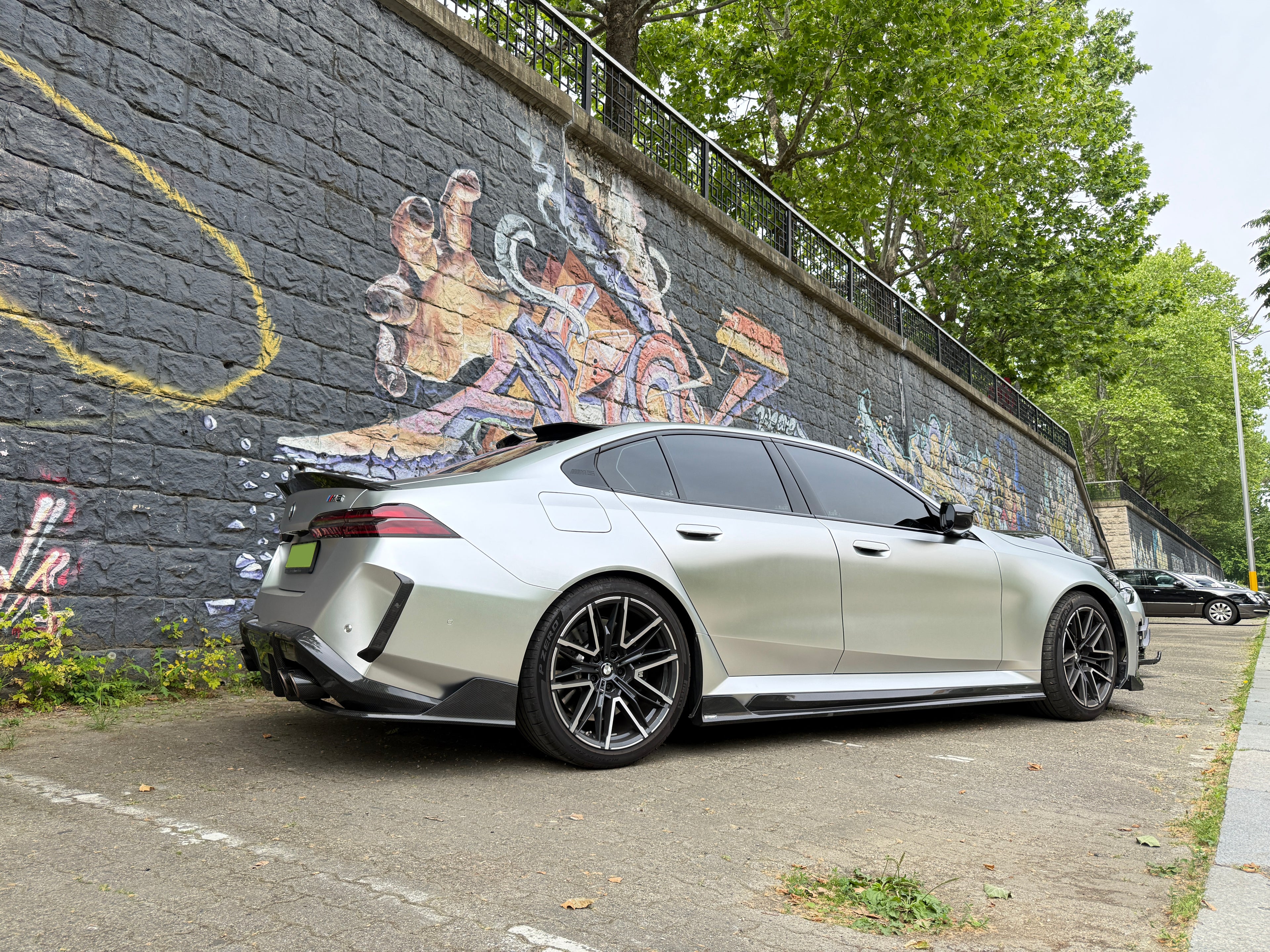 Silver Audi with carbon fiber body kit parked beside a graffiti wall, highlighting rear diffuser, side skirts, and sporty stance.