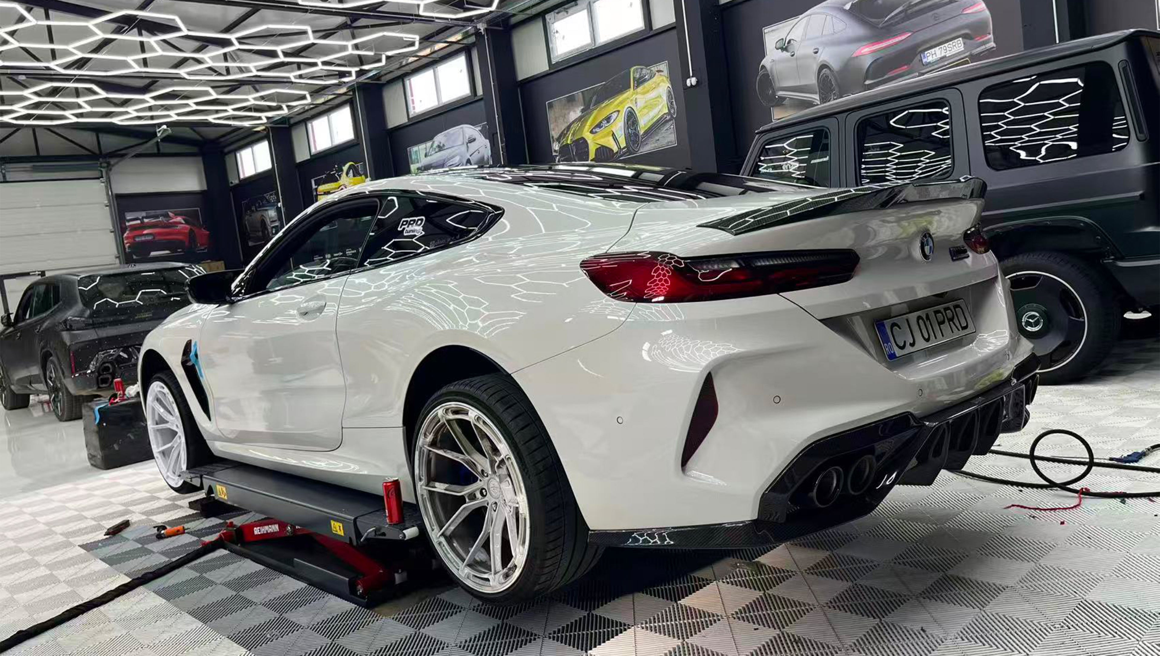 White BMW F92 M8 featuring a REVOZPORT carbon fiber front lip, side skirts, black front grille, and white multi-spoke forged wheels parked at sunset on an open road.