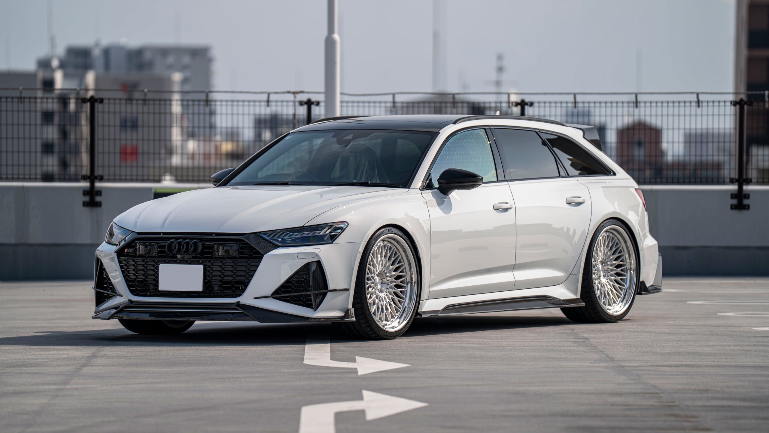 White Audi RS6 Avant featuring a REVOZPORT carbon fiber body kit with front lip, side skirts, rear diffuser, and lowered stance driving at high speed on a highway.