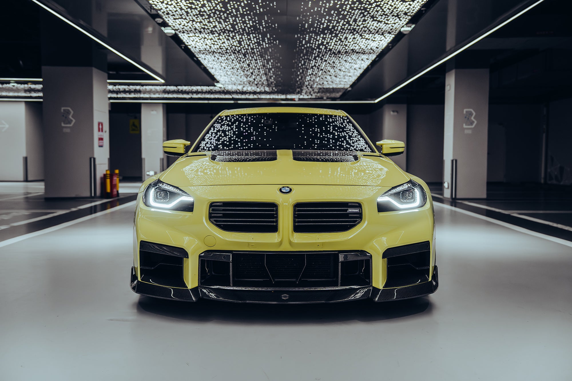 The BMW M2 is wrapped in carbon fiber, and in a high-end studio, the lights are turned on