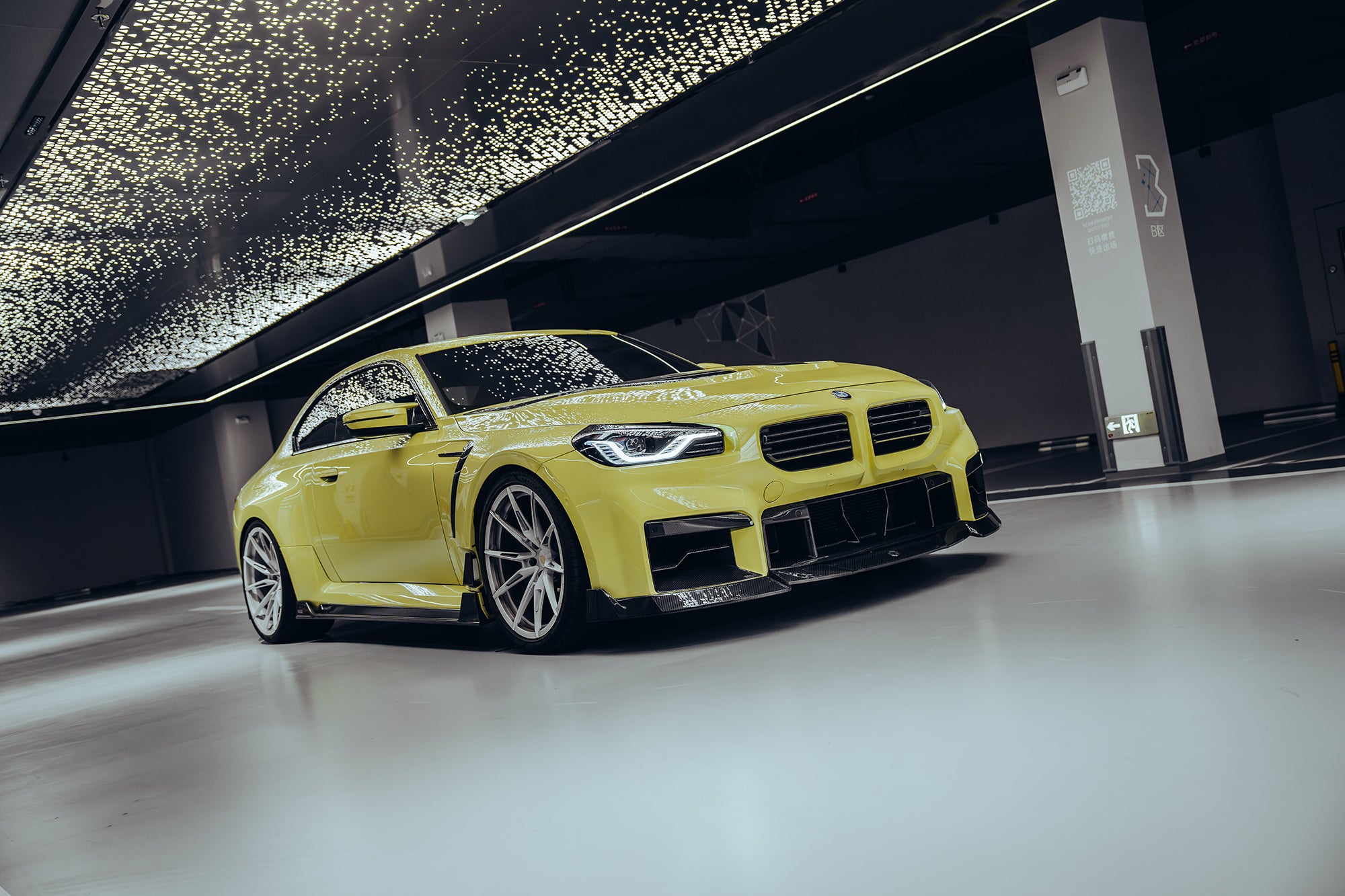 BMW with carbon fiber body kit parked outside a workshop, highlighting the aggressive front lip and side skirt design.