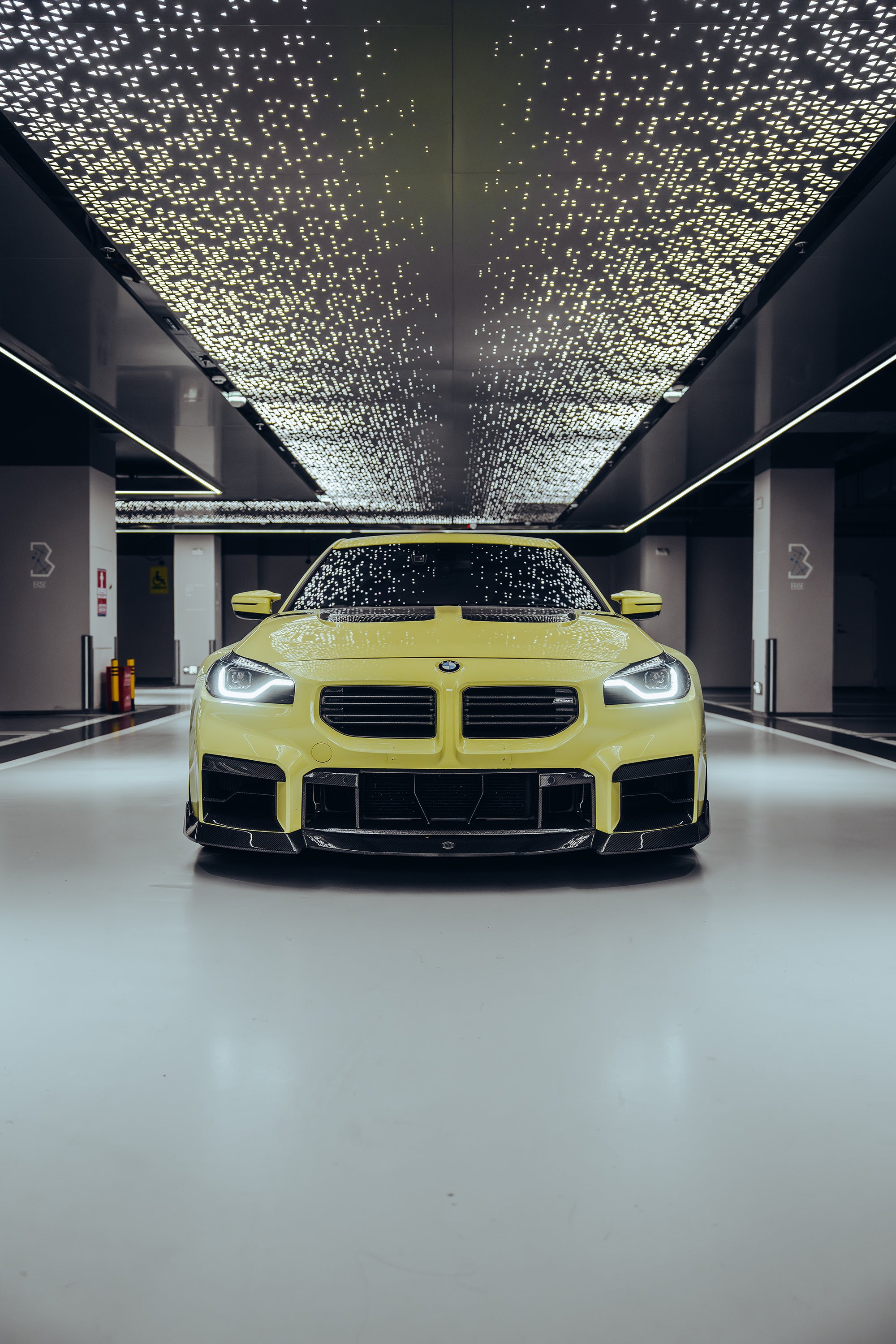 The BMW M2 is wrapped in carbon fiber, and in a high-end studio, the lights are turned on