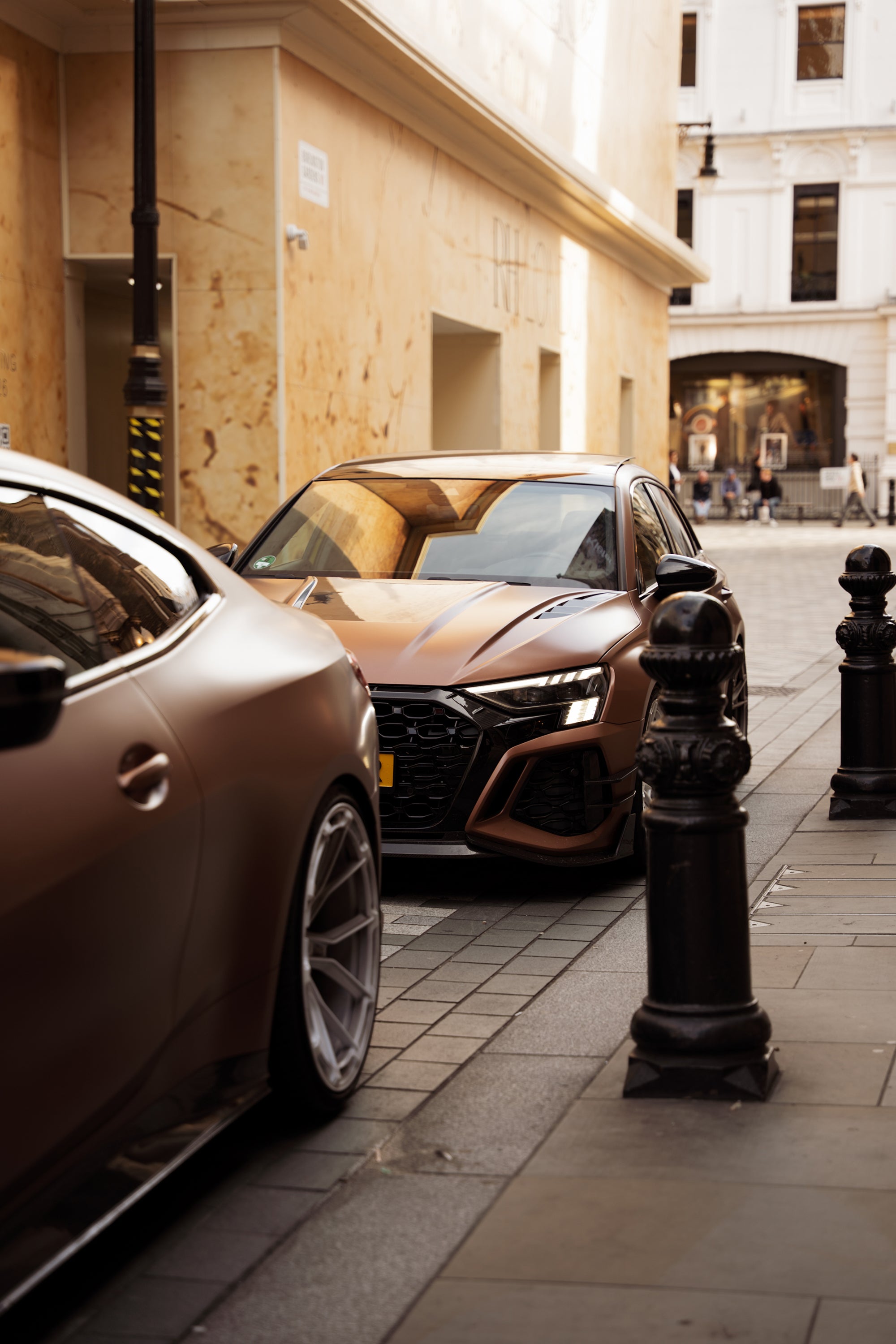 Bronze Audi RS4 Avant featuring a REVOZPORT carbon fiber body kit with front lip and side skirts, paired with silver multi-spoke forged wheels, parked in a modern urban setting.