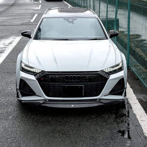 White Audi RS6 Avant featuring a REVOZPORT carbon fiber body kit with front lip, side skirts, rear diffuser, and lowered stance driving at high speed on a highway.